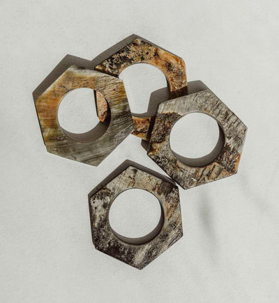 Four napkin rings shaped in a hexagon shape with different shades of brown and gray.