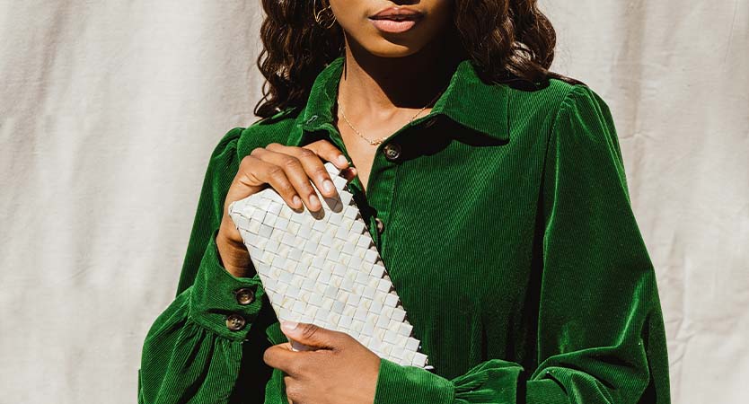 Women holding white clutch while wearing a green collared dress