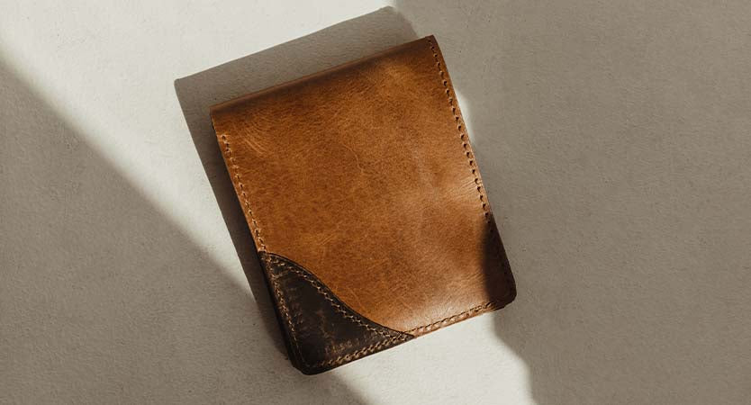 Leather Wallet with dark and light tan sections. Bifold wallet on a tan background