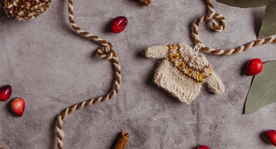 Tan sweater garland laying on a gray background with cranberries and leaves