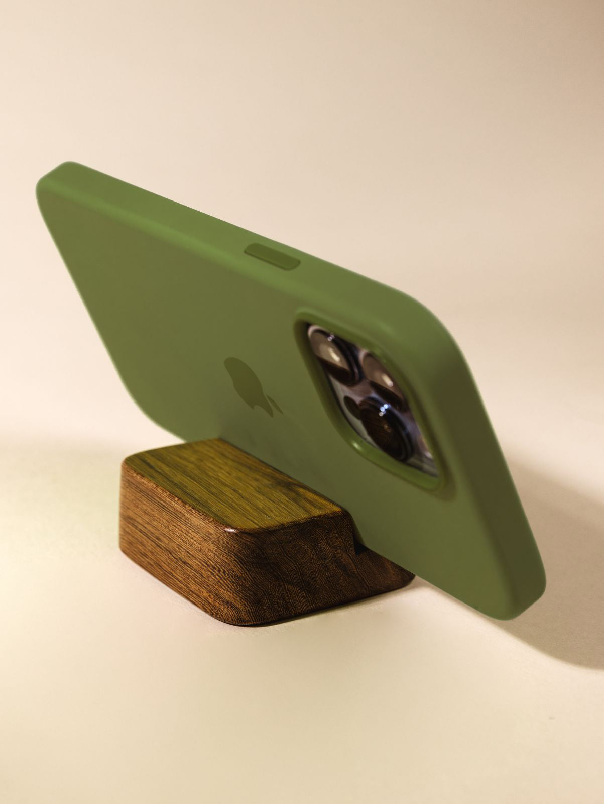 Wooden cell phone stand holding phone horizontally on cream background.