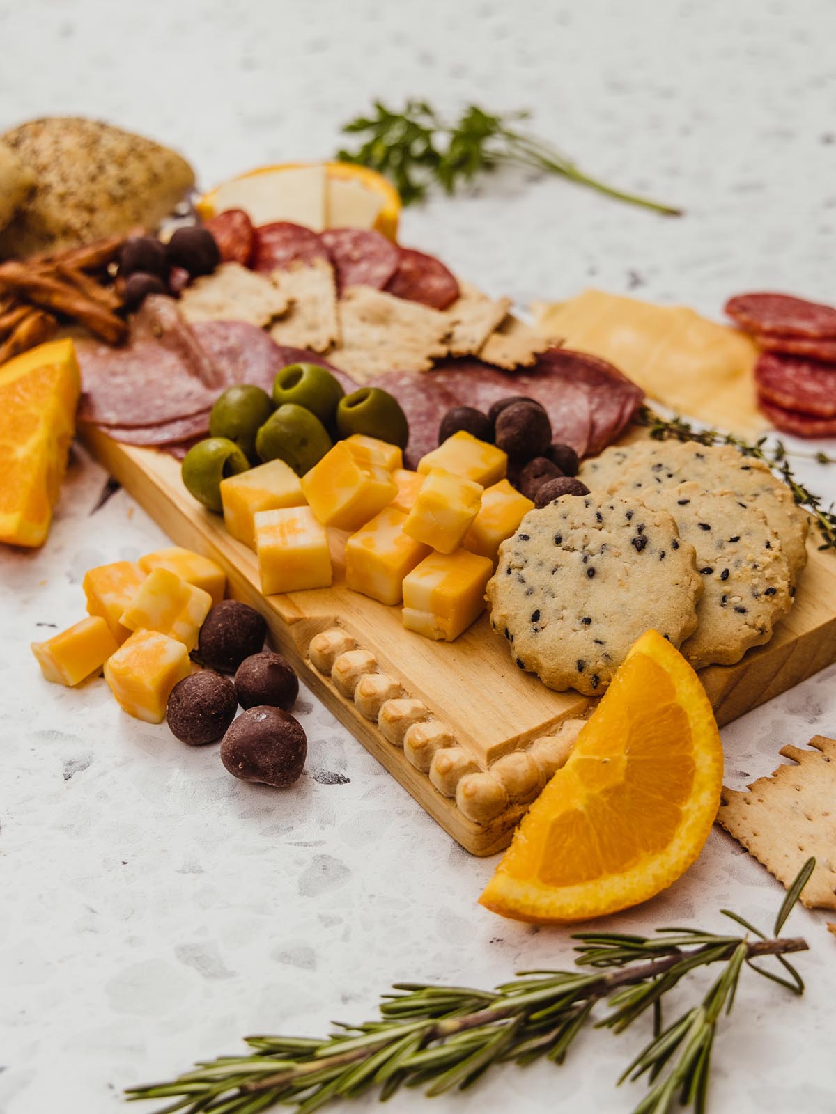 Rectangular wooden charcuterie board with meat and cheese seen on board. 