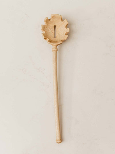 Wooden slotted pasta spoon sitting on table