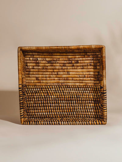 Brown woven basket in a square shape in front of a white background