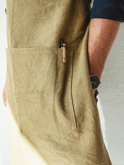A man wearing a tan apron in from of a white wall - close up of pocket
