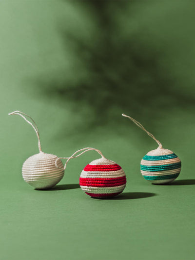one white ornament, one red striped ornament, and one blue striped ornament  on  green background