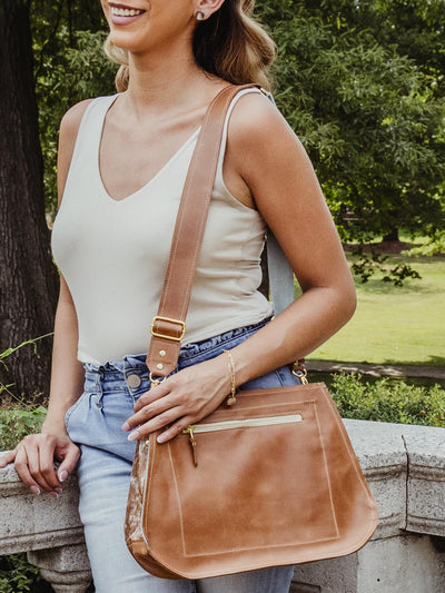 Model wearing white top and jeans with a brown leather bag