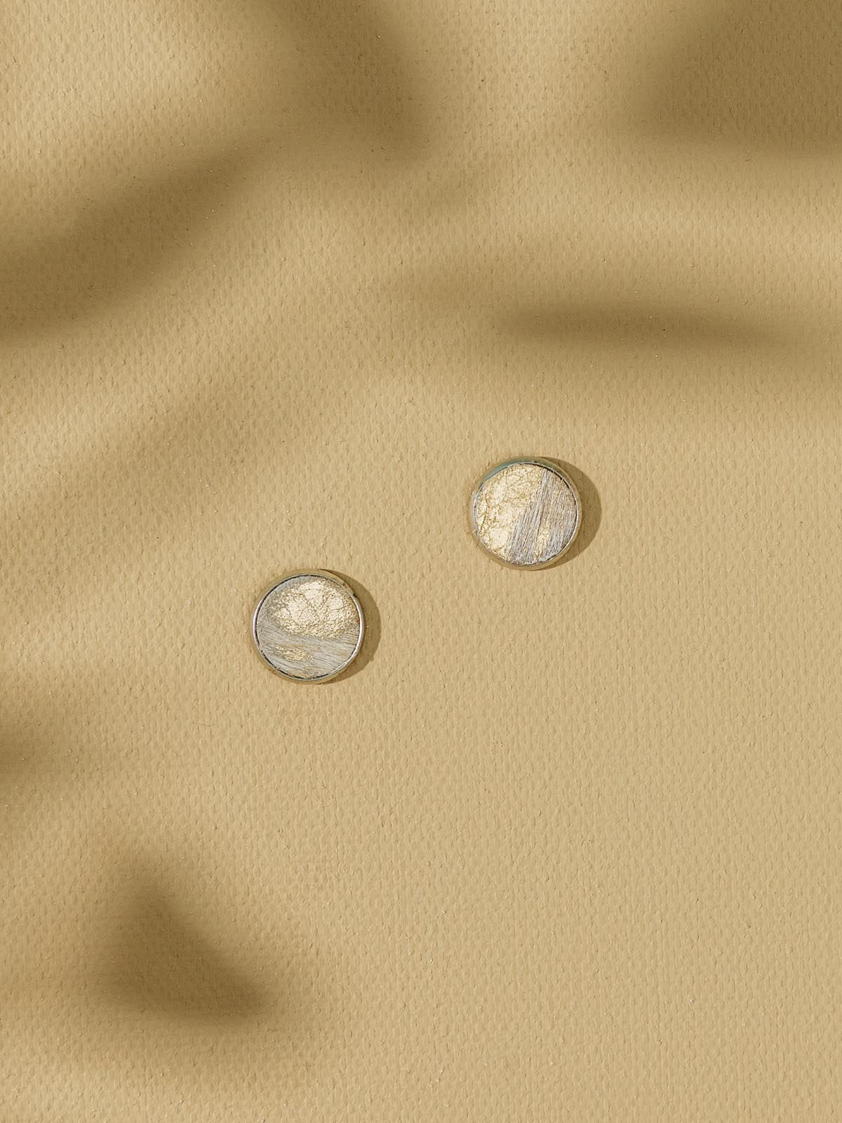 Three stud earrings on beige background