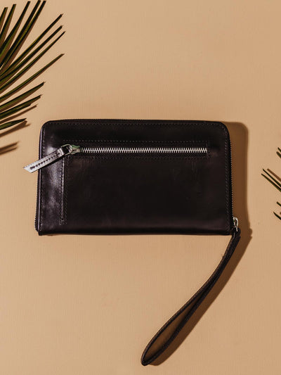 Black Rani Wallet laying on a beige table with silver detailing. 