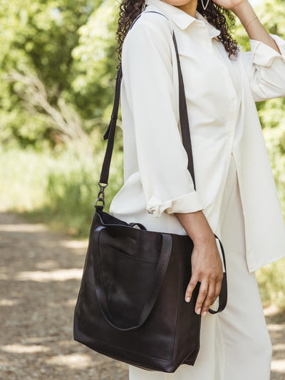 Model in an outdoor setting with made free black leather bag styled over the shoulder.