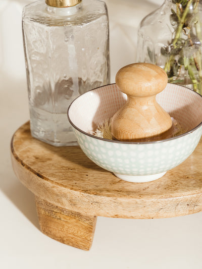 Closeup of wood mango tray with soap dispenser and brush bowl. 