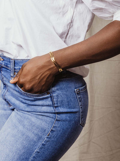 Model wearing gold cuff bracelet with casual outfit. 