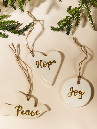 Gold Leaf Pottery Ornaments on cream background with Christmas greenery.