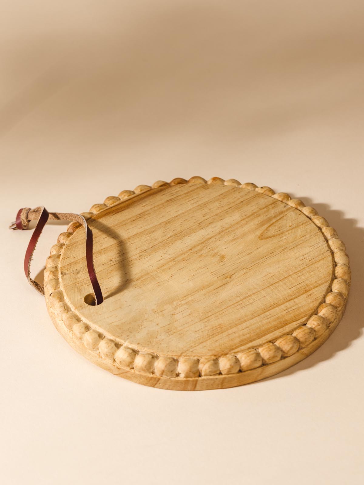 Round wooden serving tray on beige background