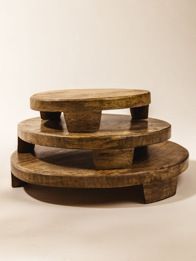Stack of three varying sizes of the wood mango tray on a cream background. Small, medium, and large mango wood trays.