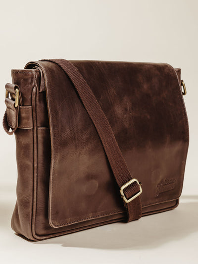 Dark brown leather Farman satchel on cream background. 