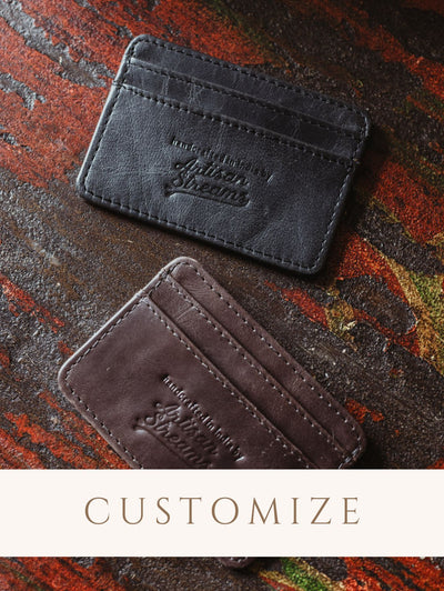 Black and dark brown minimalist wallet on wood background. Digital sticker to indicate the product is customizable.