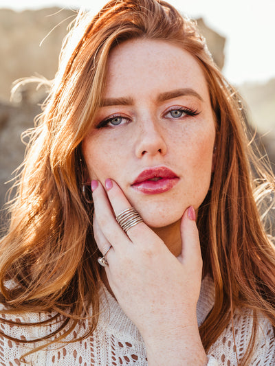Portrait of female model with red hair wearing set of 6 sterling silver stacking rings.