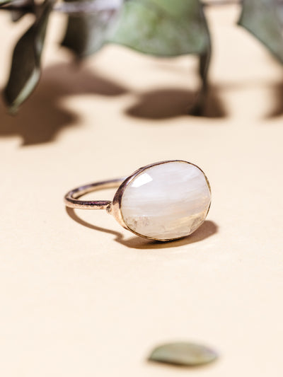Image of white moonstone ring on cream background with dried leaves