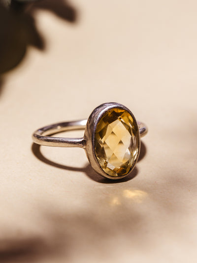 Close up of Oval Citrine Ring on cream background.
