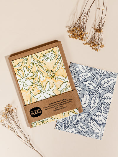 Hand drawn yellow and blue floral stationary with parchment brown envelopes on cream surface with dried flowers.