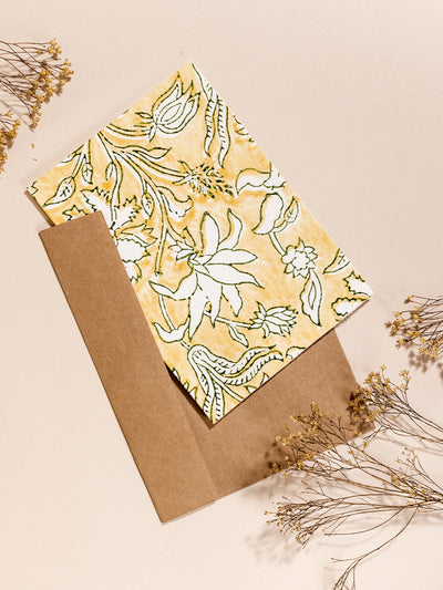 Hand drawn yellow floral stationary with parchment brown envelopes on cream surface with dried flowers.
