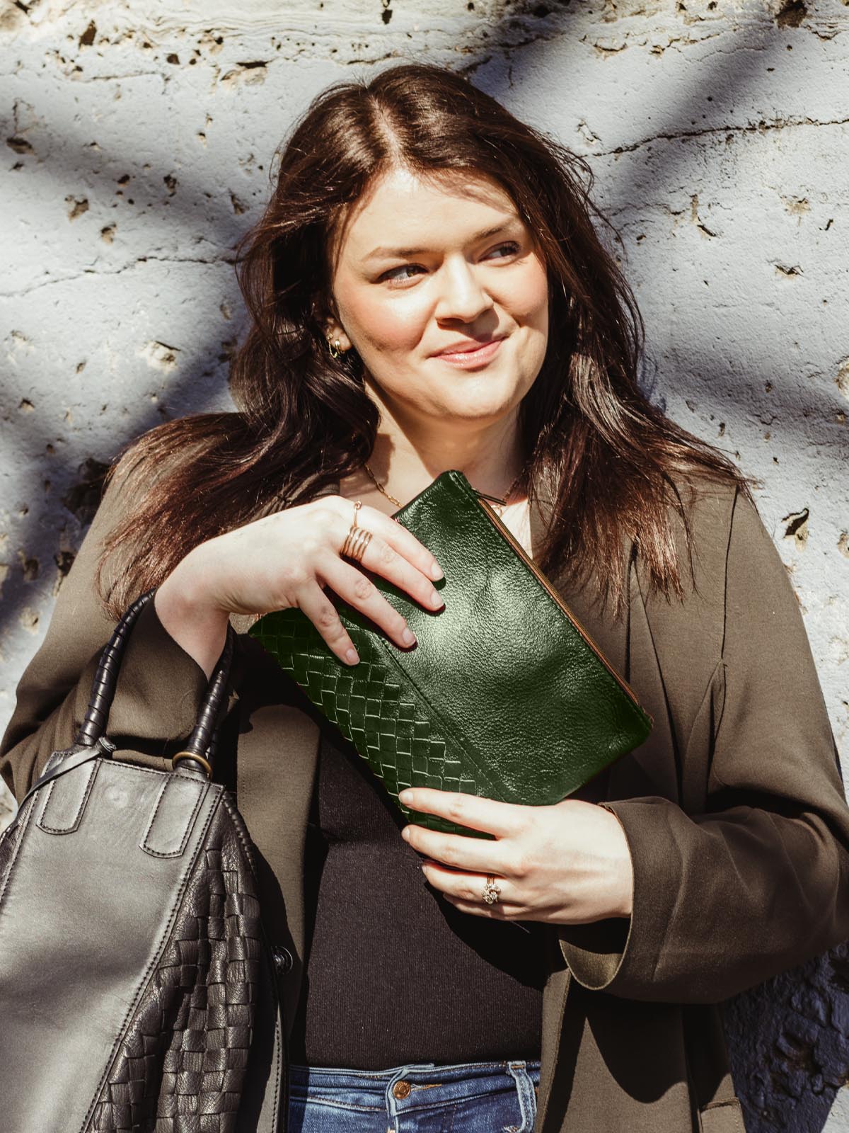 Female model holding large green pouchette.