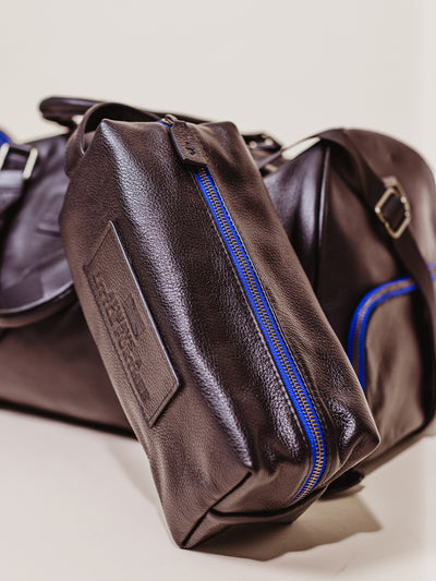 Mens black leather toiletry bag with blue accent zipper. 