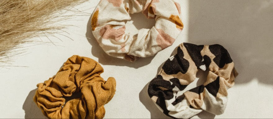 Three brownish scrunchies laid down under the light