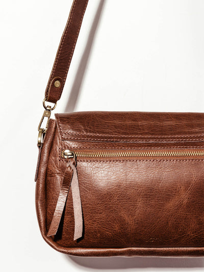 Joyn brown leather crossbody purse close up of zipper on the back of the purse on white background.