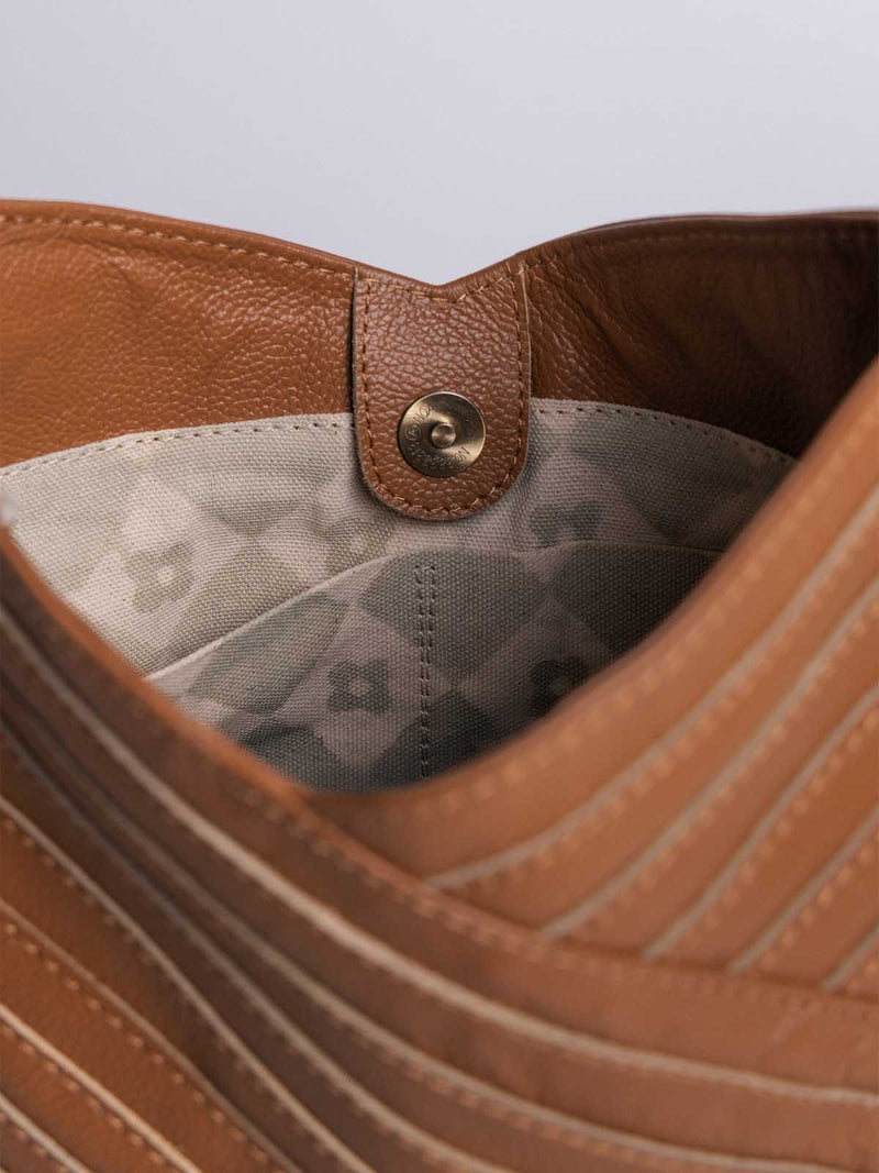 Interior view of Joffa's Crisscross brown leather handbag with a fabric lining and magnetic snap closure.