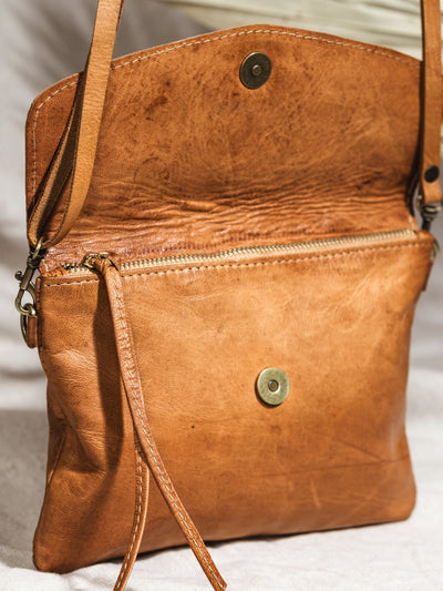 Close up of crossbody clutch flap opened to reveal snap and zipper.