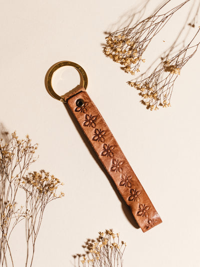 Hand Stamped Leather Keychain on cream surface with dried flowers