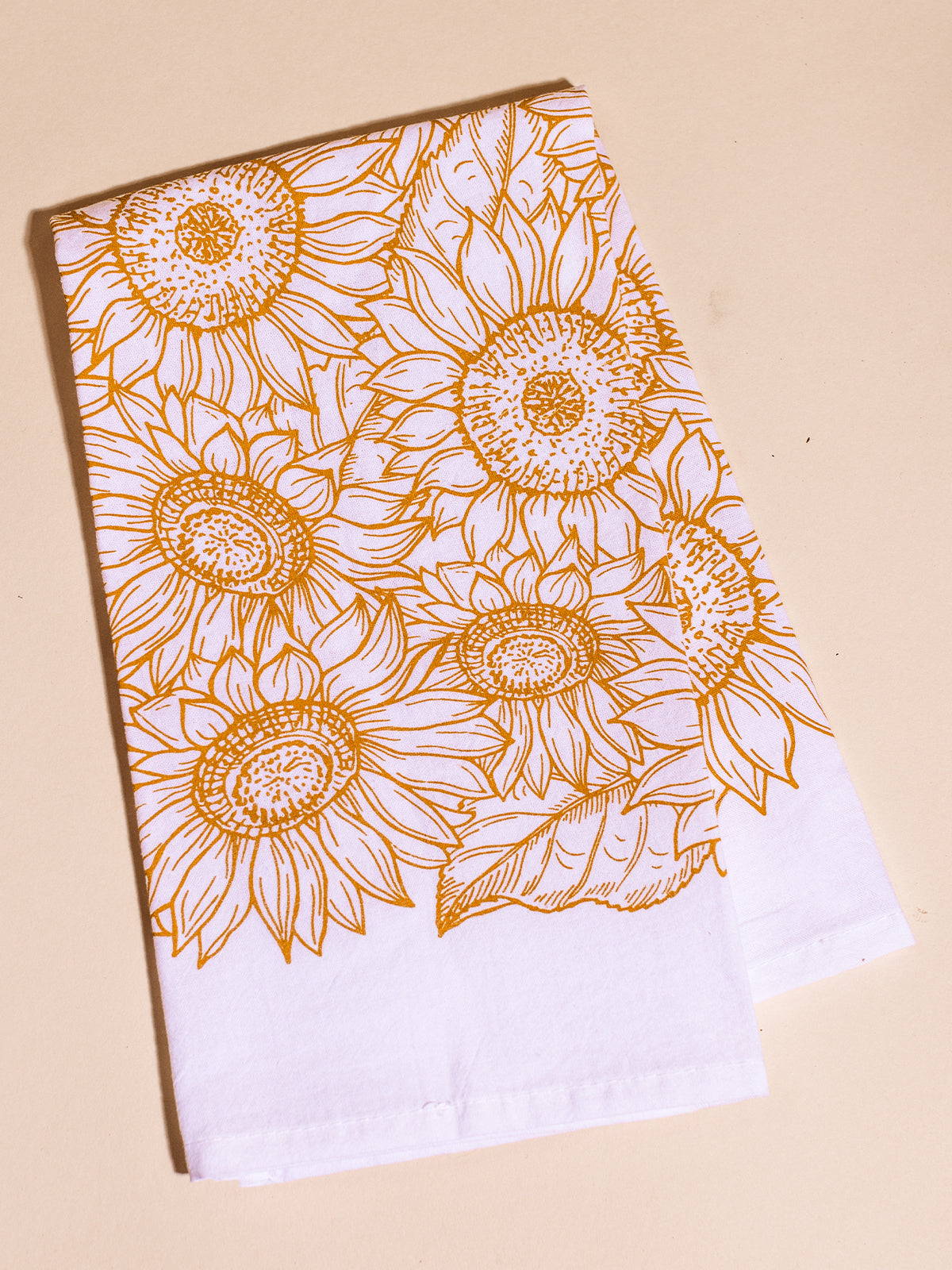 Sunflower line art printed tea towel on a cream surface.