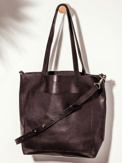 Made Free large black leather hand bag on white background showcasing hand and shoulder straps.
