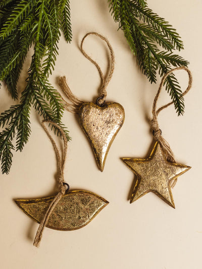 Vaara Gold Ornament Set: Bird,Hearts, Star. Ornaments on a cream background with Christmas tree greenery. 
