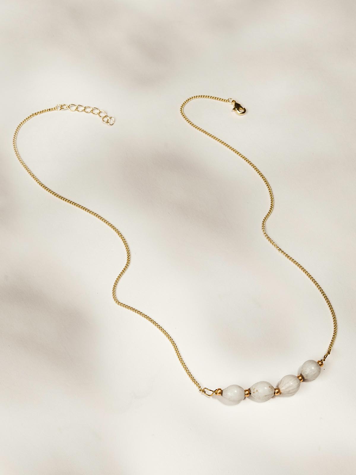 Gold necklace with four white beads