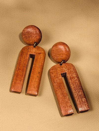 Dangling Mahogany Earrings on a tan background. With stud and arch shaped dangle. 