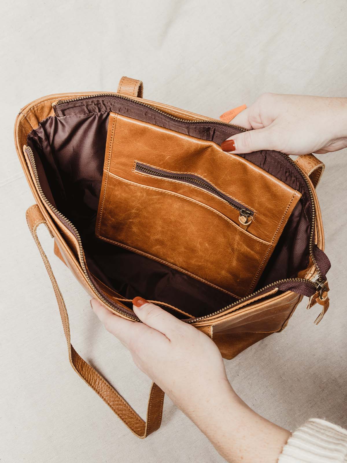 Interior closeup of the Lady's Leather Tote bag. Contains a dark brown interior lining, and hazelnut leather pouch with zipper for additional storage.