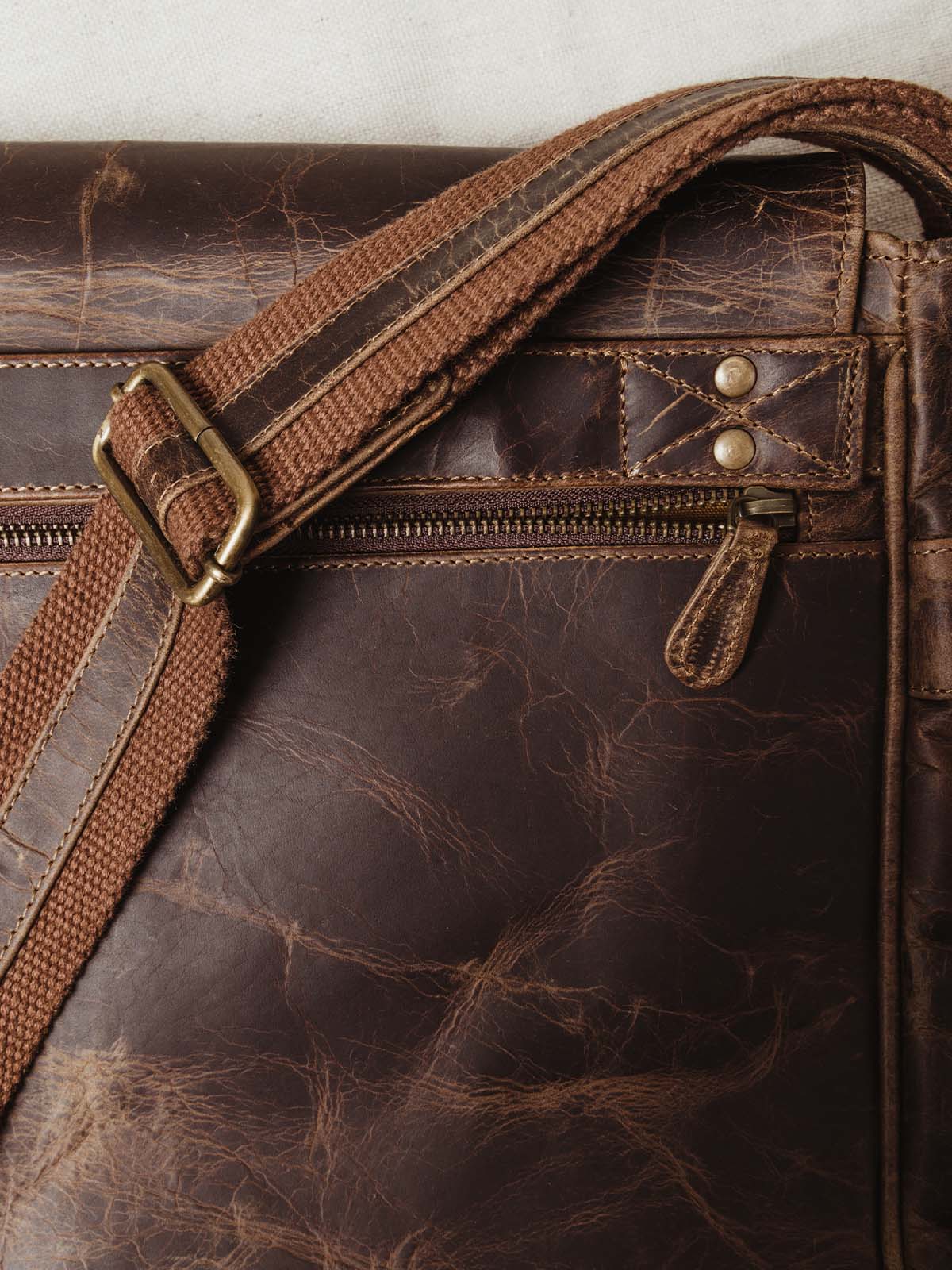 Close up of quality dark leather, exterior zipper, and adjustable shoulder strap.
