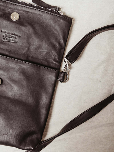 Detail of black leather and adjustable purse strap. Metal clasp, zipper and inside pocket for additional storage.