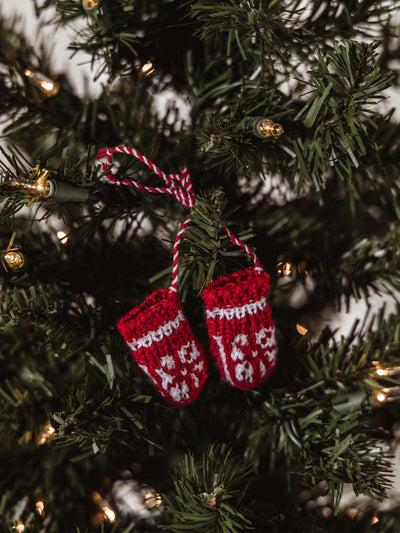 Red and white mitten ornament tied together with a red and white string and hung on a holiday tree