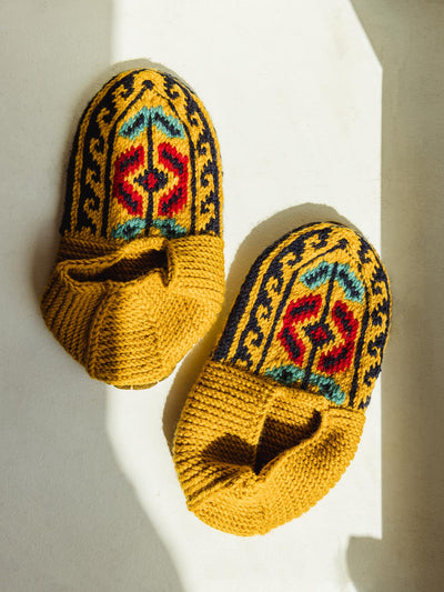 Golden yellow knitted mustard shoe/socks. Across the top is a tribal like pattern in red, blue-green, and navy.