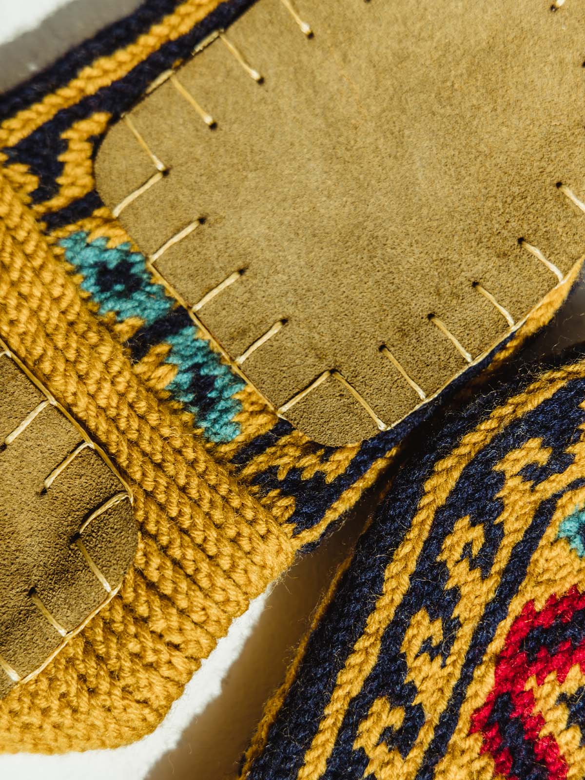 Bottom of golden yellow/mustard colored shoe/socks. Featuring  padding on the bottom much like a house shoe.  Material is tope in color and hand stitched to the sock.