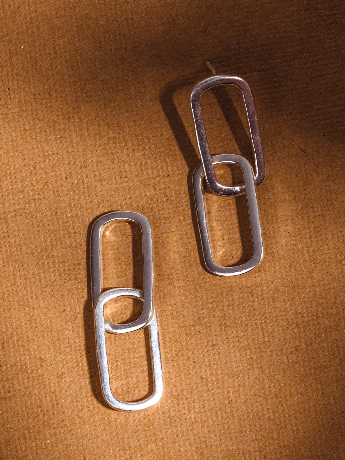 Silver earrings on a brown background