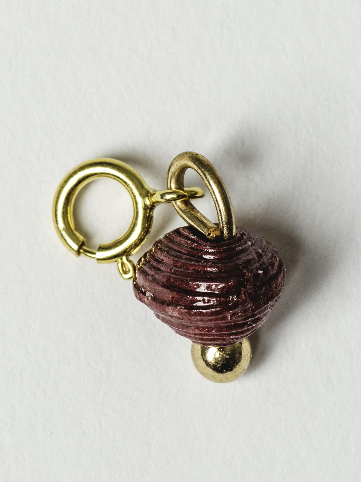 Dark red bead charm on gold clasp. 