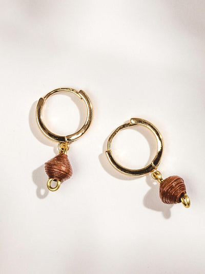 Gold hoop earrings with brown bead charm on a white surface.