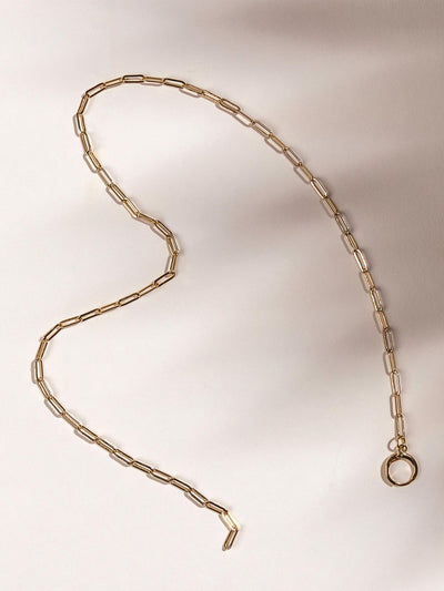 Gold chain charm necklace on white surface.