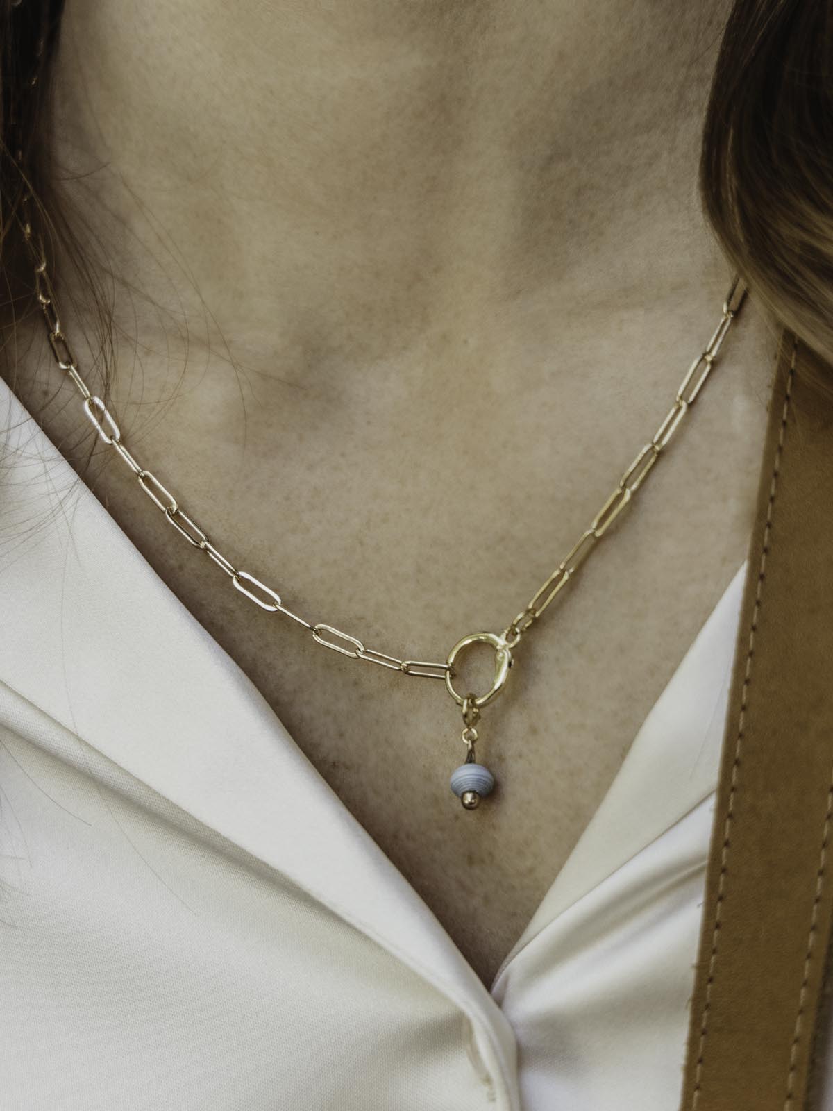 Gold Chain necklace on model with a featured light blue birthstone bead.