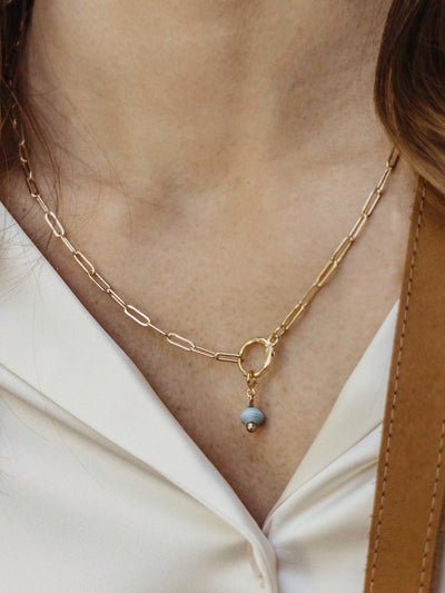 Gold Chain necklace on model with a featured light blue birthstone bead.